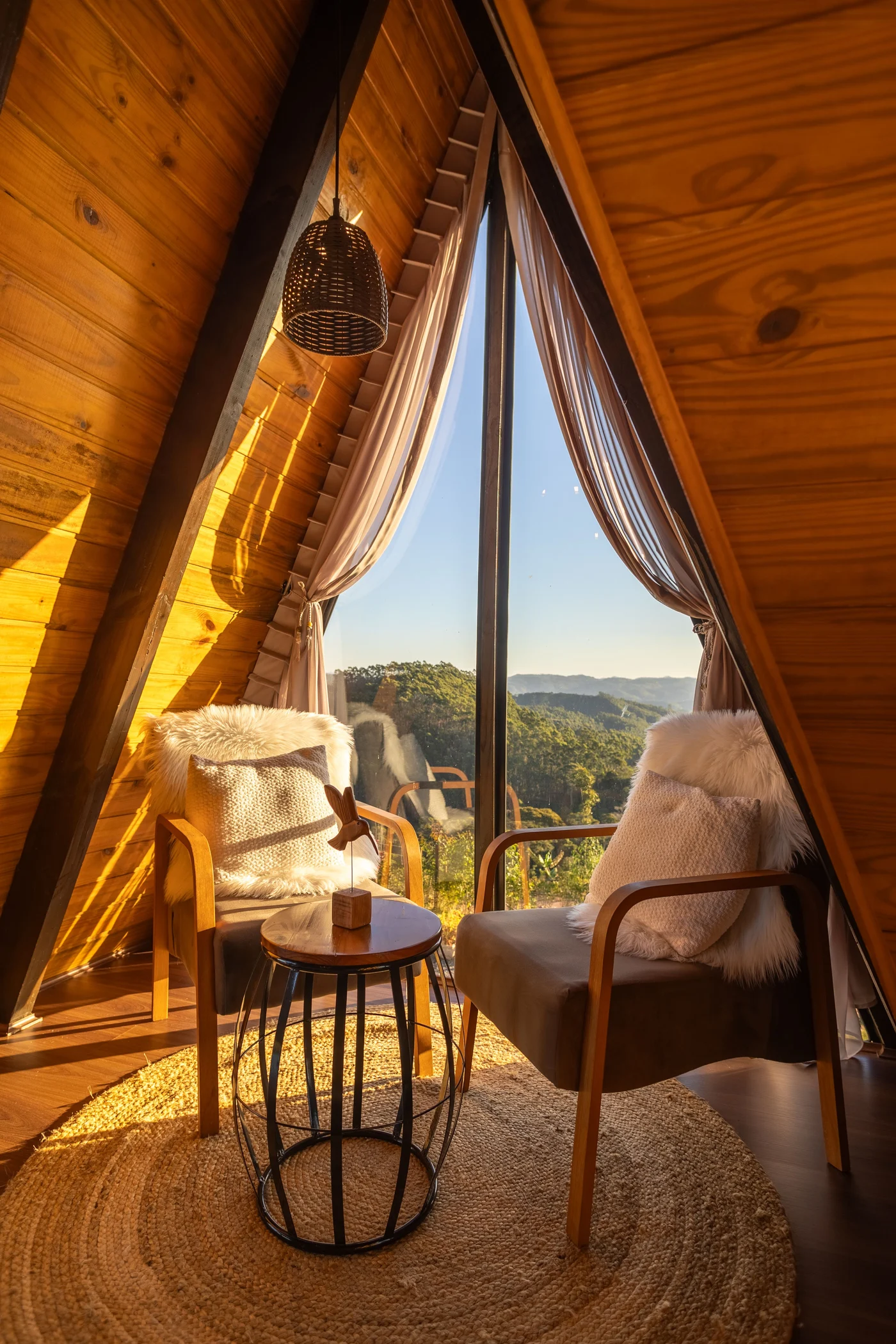 Two timber armchairs and a small round table in the sunny loft