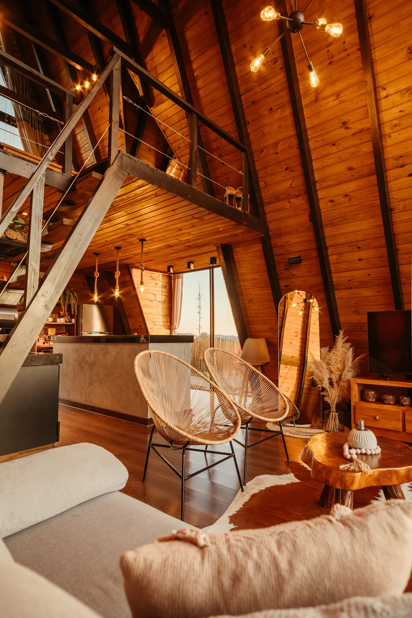 Living room facing the timber staircase, woven chairs and kitchen